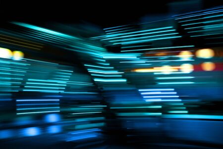 Blue and turquoise lights of urban city surrounding moving and blurred by motionの写真素材
