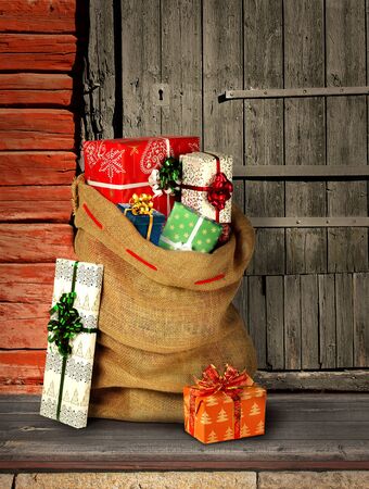 Santas present sack with gift boxes on rough wooden log cabin entranceの写真素材