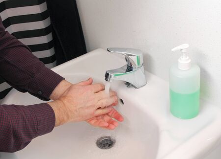 Man washing hands with soap and running water in bathroom sink, hygiene conceptの写真素材
