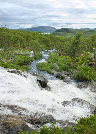 Streamlet waterfall from Lake Tsahkal in Northern Lapland wilderness, fells on the backgroundの写真素材