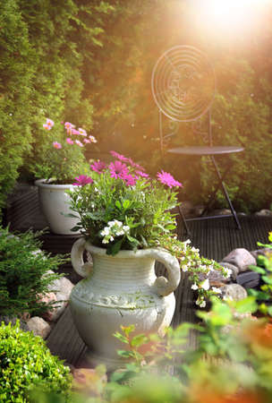 Peaceful, sunny and warm hideaway garden patio feeling with flowers in clay potsの写真素材