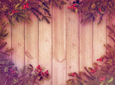 Christmas tree branches and red berries on wooden plank wall old postcard style backgroundの写真素材