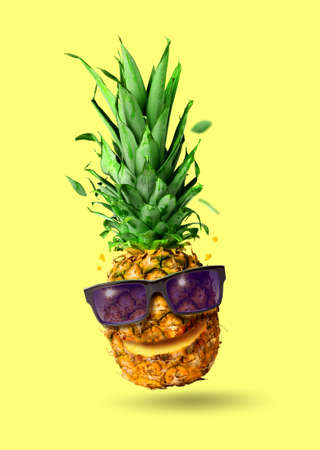 Funny tropical jumping pineapple fruit with sunglasses, holiday concept, isolated on pink backgroundの写真素材