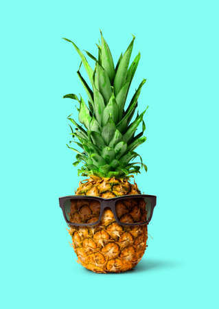 Fresh tropical pineapple fruit with sunglasses, isolated on pink background, holiday conceptの写真素材