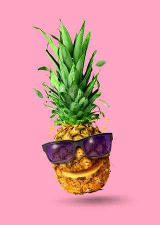 Funny tropical jumping pineapple fruit with sunglasses, holiday concept, isolated on pink backgroundの写真素材