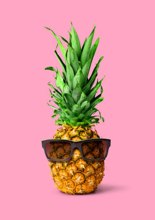 Fresh tropical pineapple fruit with sunglasses, isolated on pink background, holiday conceptの写真素材