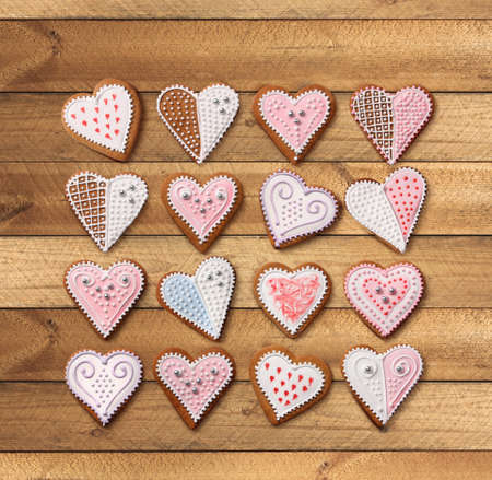 Sweet Christmas heart shaped gingerbread cookies collection with colorful sugar icing decoration, on old wooden backgroundの写真素材