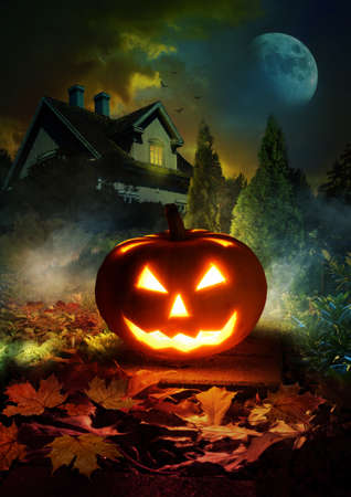 Night scene of Halloween pumpkin lantern on pathway through mystery garden to scary haunted houseの写真素材