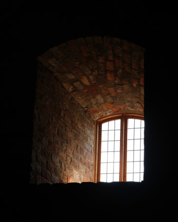 Mediaeval castle window seen inside, thick stone walls, light coming in, deep shadowsの写真素材