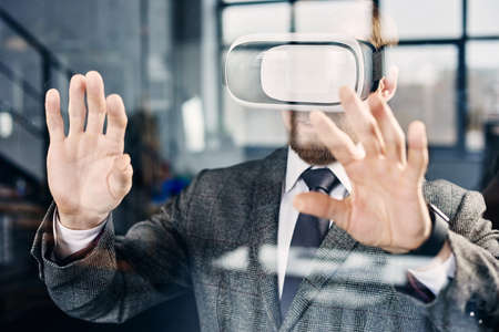 Mid age businessman in VR glasses working at the officeの写真素材