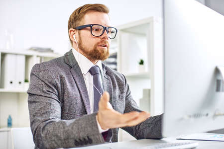 Mid age businessman talking on video call at the officeの写真素材