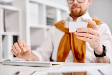 Mid age businessman working with plastic card at the computer in the officeの写真素材