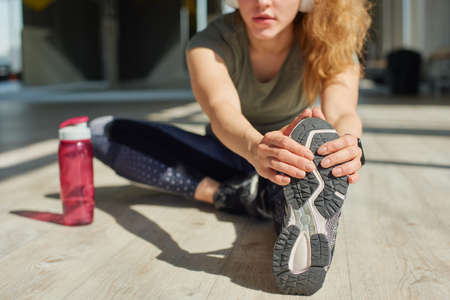 Girl in sports wear does warmnig up before the training.