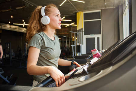 Girl in headphones running on the treadmill.の写真素材