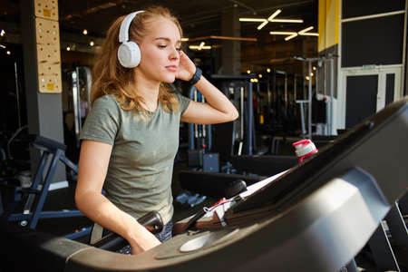 Girl in headphones running on the treadmill.の写真素材