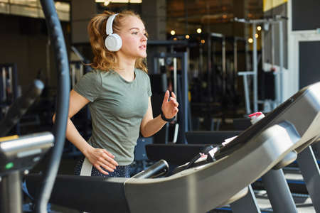 Girl in headphones running on the treadmill.の写真素材