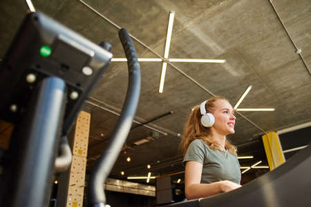 Girl in headphones running on the treadmill.