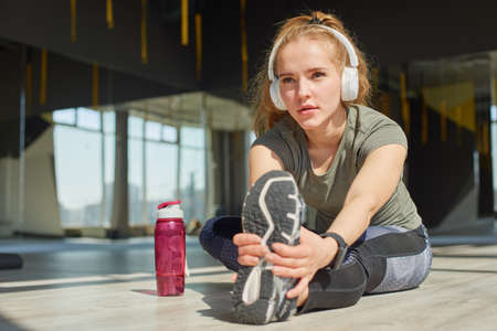 Girl in sports wear does warmnig up before the training.