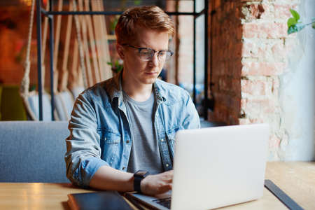 Young man works on the laptop in the cafe.の写真素材