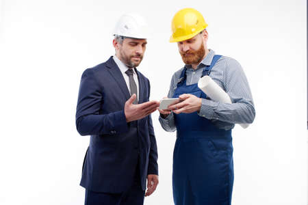engineer and foreman look at the phone on a white backgroundの写真素材
