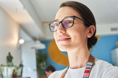 Beautiful barista in glasses drinks coffee and smiles.の写真素材