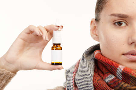 Close-up. The girl with a runny nose holding drops in his hands
