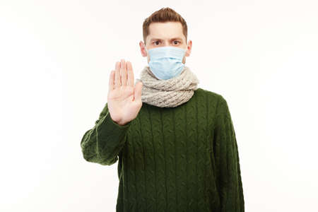 Man in a green sweater wears medical mask.の写真素材