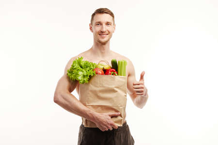 The athlete is holding a package with healthy products on a white backgroundの写真素材