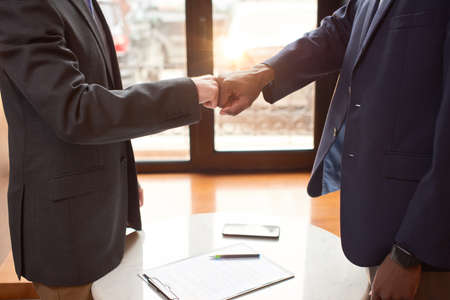 Two man shaking each others hands after signing papers.