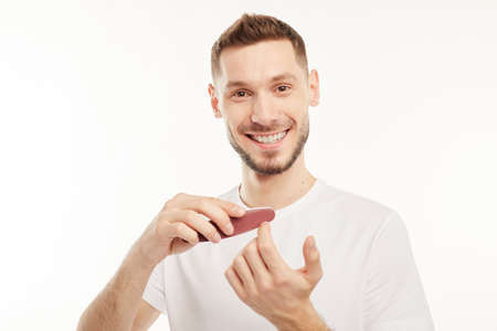 Man holds and uses nail file smiling at the camera.の写真素材