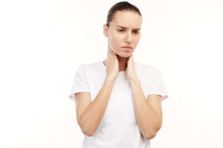 Woman in white t-shirt having muscular pains in neck.の写真素材