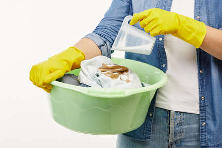 Close up of a woman in work-wear holding a green bucket full of washing.の写真素材