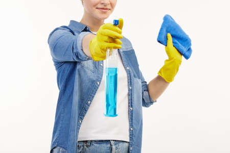 Pretty woman in work-wear uses window cleaning supplies in a close-up.