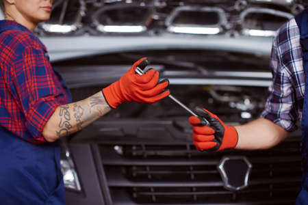 Two mechanics work under repairing a microbus.