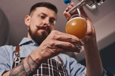 Close up of bartender at work pouring beer.の写真素材