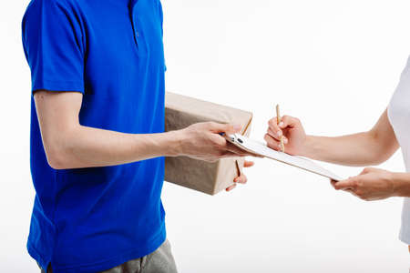 Close up of a mailman giving the parcel full of papers to the female client.