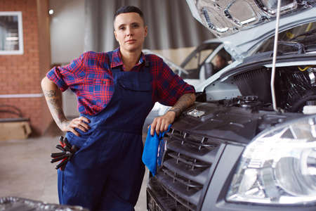 Vertical portrait of a woman automechanic standing next to a broken truck.の写真素材
