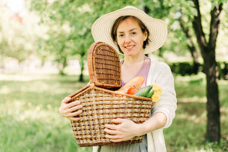Woman in a straw hat holds big picnic basket.の写真素材