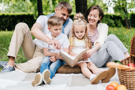 Portrait of a family at the picnic reading a book.の写真素材