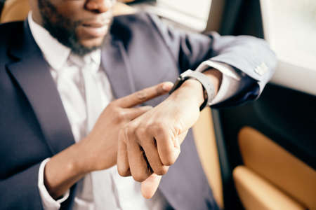 Close up of a man checking time on his watch he wears during car ride.の写真素材