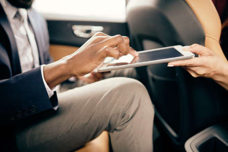 Close up of a man scrolling through tablet screen someone else holds for him.の写真素材