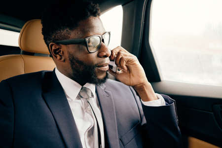 Businessman sits in the car and has conversation on the phone.の写真素材