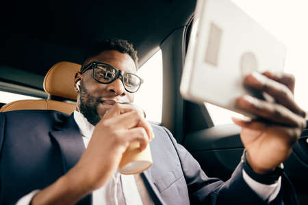 Man looking at the tablet screen and drinking coffee.の写真素材