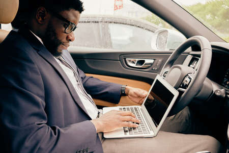 Businessman works on the laptop sitting in the car.の写真素材
