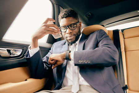 Man in car talks on the loud phone mode and looks at the watch.の写真素材