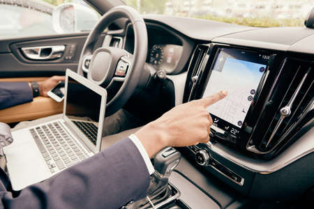 Close up of a driver using different devices he has located in car.