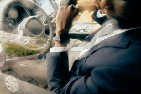 Close up of a man looking at his watch he is wearing on driver's seat.の写真素材