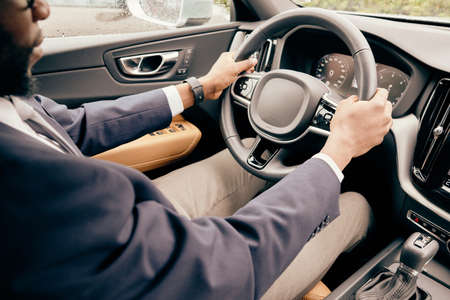 Man holds car's steering wheel with his two hands being on the driver's test.