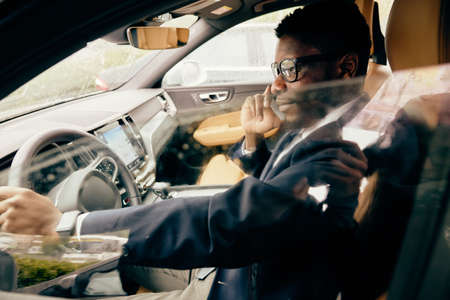 Businessman sits in the car and has a work-related conversation on the phone.