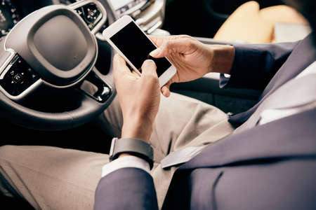 Man scrolling through the feed on his phone while sitting on the front car seat.